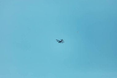 Bir spor uçağı gökyüzünde yükseklerde uçuyor. Hava dalışı için bir yolcu uçağı izleyicinin kafasının üzerinden uçuyor.