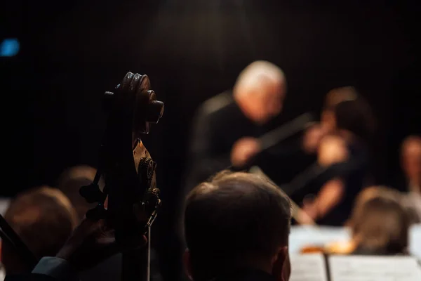 conductor in the dark. a man in a formal suit controls the musicians in the orchestra. symphony music concert