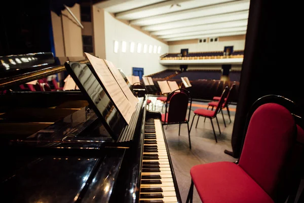 Sahneden boş konser salonunun manzarası. Sahnede müzisyenler için sandalyeler ve enstrümanlar var. Ünlü orkestranın performansı için filarmoni orkestrasının hazırlığı