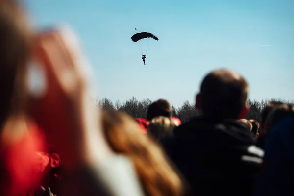 观众在着陆伞兵背景下的轮廓 跳伞运动员从高空从飞机上跳下的演示表演 极限运动节 — 图库照片