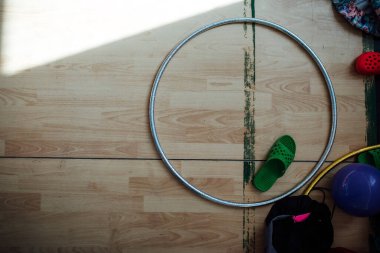 Bir kız çemberle ritmik jimnastikte gösteri yapıyor. Hakemlerin önünde esneklik ve maharet için bir spor müsabakası. Akrobatın performansının karmaşık unsurları