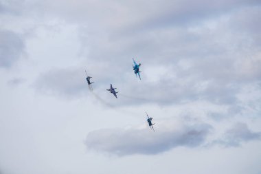 Dört jet uçağı sıkı bir düzende uçuyor. Pilotlar, havacılık festivalinde tehlikeli akrobatik hareketleri gösteriyor. Modern savaş uçaklarının askeri geçit töreni