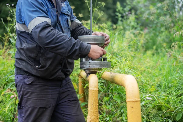 Üniformalı bir adam gaz borusunu tamir etmekle, ekipmanları aletlerle tamir etmekle, demir iletişim tamirciliğiyle, onların durumunu iyileştirmekle ve insanların güvenliğini sağlamakla meşgul.
