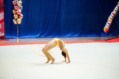 Bir jimnastikçi kız potayla gösteri yapıyor. Esnek sporcu yarışmalarda amuda kalkar.