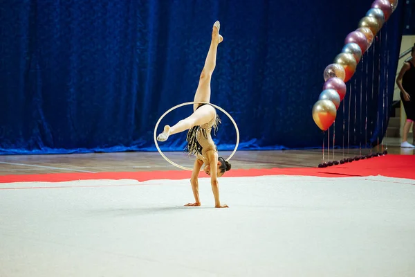 体操選手の女の子がフープで演奏します 柔軟なアスリートが競技会で手を取り合う — ストック写真
