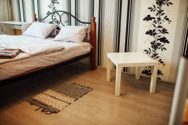 Apartman dairesinde hazır yatak. Çift katlı yatak. Dairenin parlak renkli minimalist iç mekanı. Otel odasındaki yumuşak, temiz çarşaflar. Komodin ve sandalye.