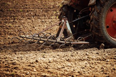 Tarımsal bitkiler için tarla sürücüsü toprağı sürüyor. Çiftçi ilkbaharda tohum ekmek için toprağı işliyor. Makinenin demir pulluğu