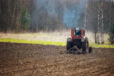 Bir traktör tarlayı sürüyor. tarım arazilerinin ekilmeye hazır hale getirilmesi. Mekanik bir saban toprağı çizer. Bereketli toprakların yetiştirilmesi