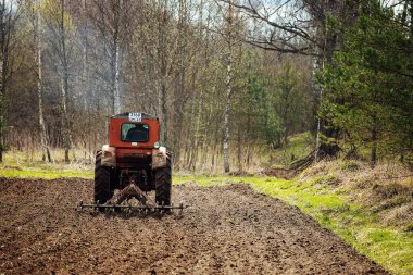Bir traktör tarlayı sürüyor. tarım arazilerinin ekilmeye hazır hale getirilmesi. Mekanik bir saban toprağı çizer. Bereketli toprakların yetiştirilmesi
