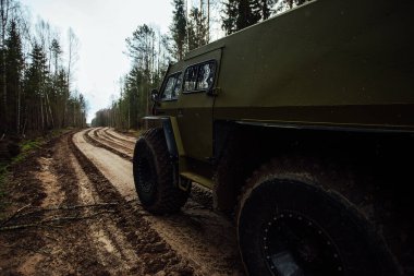 Dört teker çekişli arazi aracı ormanın içinden çamurun içinden geçiyor. Büyük tekerlekleri ve yüksek izinleri olan geçilebilir bir SUV. Ormancılar için özel ulaşım bataklıklar ve çamurda yolculuk ediyor.