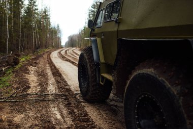 Dört teker çekişli arazi aracı ormanın içinden çamurun içinden geçiyor. Büyük tekerlekleri ve yüksek izinleri olan geçilebilir bir SUV. Ormancılar için özel ulaşım bataklıklar ve çamurda yolculuk ediyor.