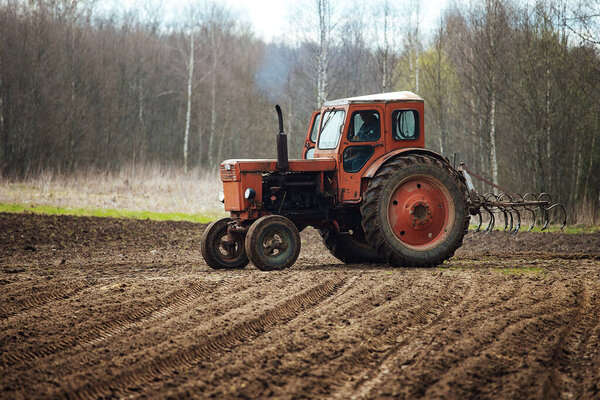 a tractor plows a field. preparation of agricultural land for planting. a mechanical plow makes furrows in the soil. cultivation of fertile land