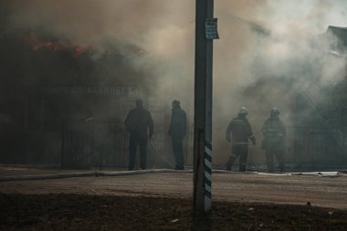 Bir kurtarma ekibi evdeki yangını söndürdü. İtfaiyeciler alevlerin üzerine su döker. Yanan binadan duman ve sis
