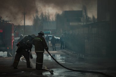 Bir kurtarma ekibi evdeki yangını söndürdü. İtfaiyeciler alevlerin üzerine su döker. Yanan binadan duman ve sis