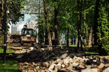 Eski kaldırım taşlarını sökün. Parkın arka sokağı yenileniyor. Yaya yolları eski fayansı yenisiyle değiştirilerek onarılır. Kırık kaldırım taşları yerde yatıyor.
