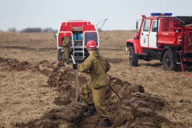 Sahada bir ateş şeridi. İtfaiye yangını yangın hortumundan çıkan suyla söndürüyor. Öfkeli ateş elementiyle savaşıyor. Orman yangınları yüzünden doğal afet