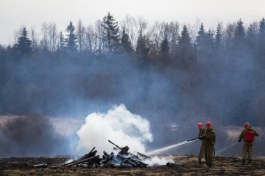İtfaiyeciler küllerin üzerinde. Yangını söndürme işini tamamladım. Yanan evdeki yanmış odun parçalarının incelenmesi. Sis ve yanık kokusu.