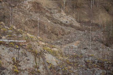 Bir atık alanı çevreyi kirletir. Endüstriyel atıkların kiri arazide yatıyor. Kamyonlar ve buldozerler çöp sahasında ev atıklarını eziyorlar.