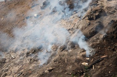 Yanan bir atık sahasından duman. Çevreye zararlı zehirli ve havada keskin bir duman var. Plastik yanıklar, atmosfere sera gazı salıyor. Çevresel bir felaket. Yüksek bir dağ...