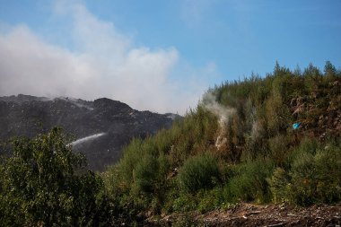 Çöp sahasında yangın. Yanan plastikten kaynaklanan zehirli atık bulutu. Çöp sahasında çıkan yangından kaynaklanan zararlı emisyonlar. Çöp yanıkları ve dumanlar metan gazı üretiyor. Çöp sahasındaki yangını söndürmek
