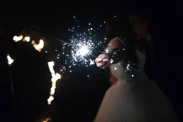 情人手里拿着炽热的火花 闪烁着火花的蜡烛照亮了正在接吻的新娘和新郎 婚礼在傍晚结束 — 图库照片