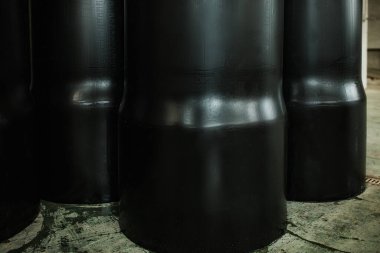 Siyah plastik ve metal borularla dolu bir depo. Boru hattı üretimi için bir fabrika. Ürünler satışa çıkarıldı. çok özdeş silindirik borular