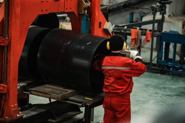 Boru döken bir fabrikada çalışan bir işçi. Demir metalurji girişiminin taşıyıcı hattı. Üniformalı bir işçi metal kaynakçılığıyla meşgul.