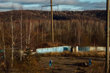 Sonbahar endüstriyel manzarası. Yaprak dökümü döneminde orman ve terk edilmiş sanayi binaları. Banliyödeki elektrik hatları. Eski fabrikanın atölyeleri