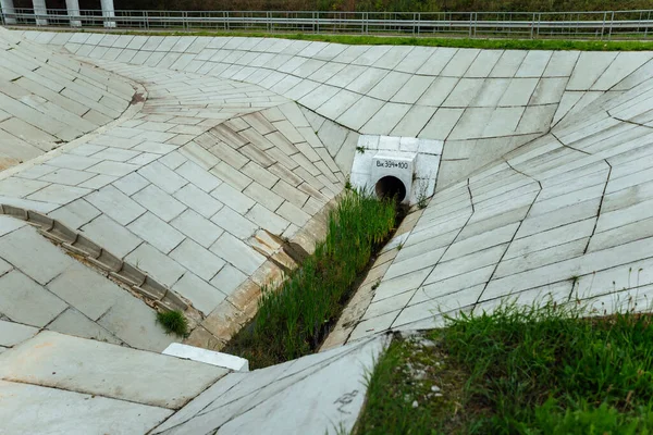 the drain of the overpass. drainage drainage system under the automobile bridge. cement drain and collector pipe going underground. storm sewer