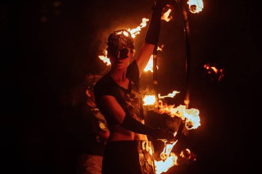 Efsanevi bir yaratığın maskesi içindeki bir ateş sanatçısı ateşle gösteri yapıyor. Sokak kültürü festivali. Geceleri renkli mistik ateş gösterisi