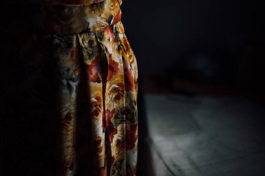 Bir mankenin üzerinde el yapımı parlak bir elbise. Moda tasarımcısı bireysel terzilikten bir elbise yapar. Çiçek desenli kumaş. Siyah arka planda bir mankenin üzerindeki kıyafetlerin fotoğrafı.