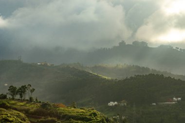 Güneş ışınları soğuk bir öğleden sonra bulutları delip geçer ve bir dağ köyünün evlerini aydınlatır.