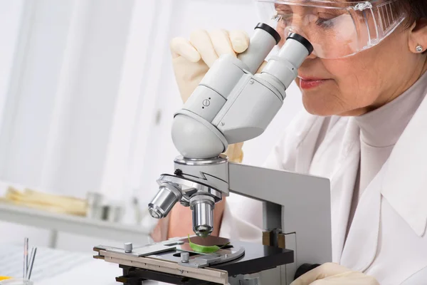 Biólogo mirando a través de un microscopio — Foto de Stock