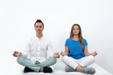 Sakin bir çift evde birlikte meditasyon yapıyor, düşünceli barışçıl bir adam ve kadın Lotus pozisyonunda yoga yapıyor.