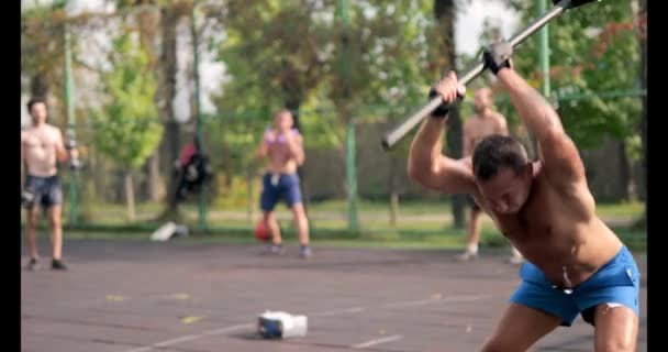 Man on Sportsground. Playing sports. He picks up hammer and hits the wheel. Cardio, strength training. Workout out. — Stock Video