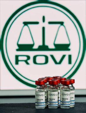 MALLORCA / SPAIN - 17 Kasım 2020: Rovi ilaç laboratuvarı Coronavirus için Moderna aşısı (Covid 19) üretti. Arka planda Rovi İlaç Şirketi logosunun bulunduğu sıra sıra sıra aşı şişeleri bulanıklaştı.