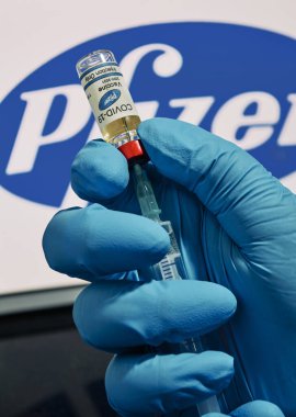 MALLORCA / SPAIN - 17 Kasım 2020: Pfizer Biontech araştırma Coronavirus (Covid 19) aşısı. Arka planda bulanık Pfizer şirket logosu olan aşı şişeleri..