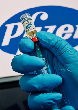 MALLORCA / SPAIN - 17 Kasım 2020: Pfizer Biontech araştırma Coronavirus (Covid 19) aşısı. Arka planda bulanık Pfizer şirket logosu olan aşı şişeleri..