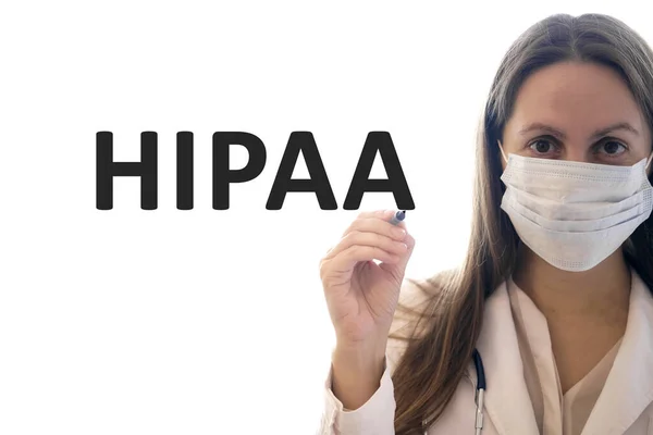 마스크를 쓴 의사가 펜을 들고 HIPAA 텍스트를 작성 스톡 사진