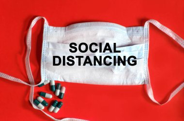 Sosyal uzaklık - koruyucu yüz maskesi üzerinde metin, kırmızı arka planda tabletler