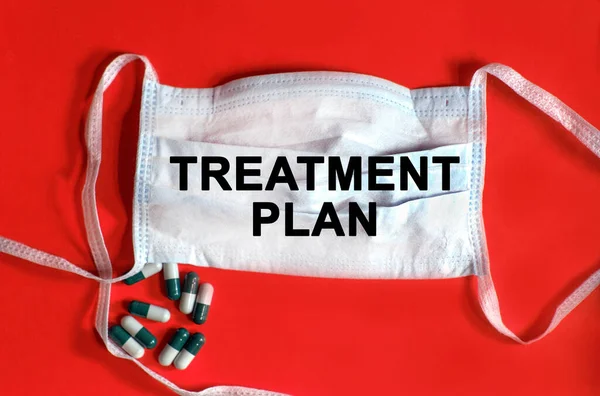 Treatment plan - text on a protective face mask, tablets on a red background