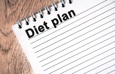 Diyet Planı - Ahşap bir masa üzerinde çizgileri olan beyaz bir defter üzerindeki siyah metin