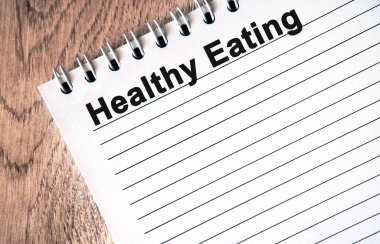 Sağlıklı beslenme - beyaz bir defter üzerinde siyah metin ahşap bir masa üzerinde çizgiler