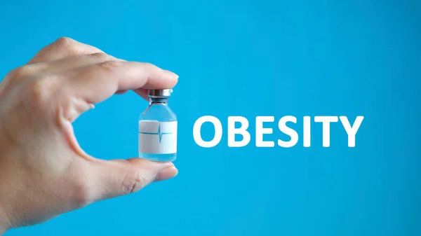 Text obezity v ruce muže držícího lahvičku s lékem na uzdravení — Stock fotografie