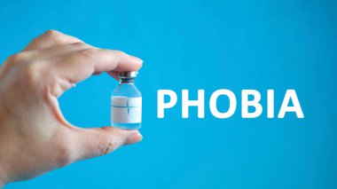 Elinde ilaç şişesi olan bir adamın elinde fobi metni var.