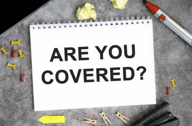 Beton bir masanın üzerinde beyaz bir defter, raptiye, kalem ve zımba var mı?