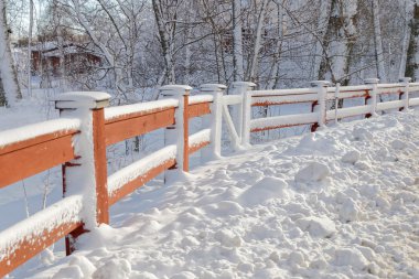 Kırmızı çit karla kaplı, arka planda ağaçlar
