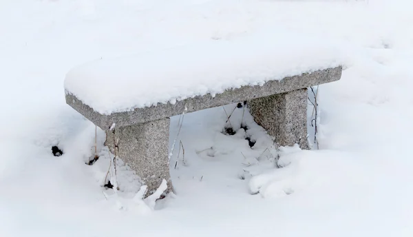 Banco de pedra coberto de neve — Fotografia de Stock