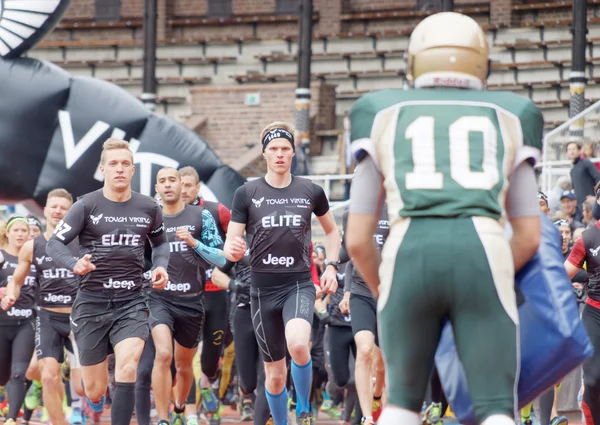 stock image STOCKHOLM, SWEDEN - MAY 14, 2016: Lots of runner trying to pass the first obstracle, american football players, after the start in the obstacle race Tough Viking Event in Sweden, April 14, 2016