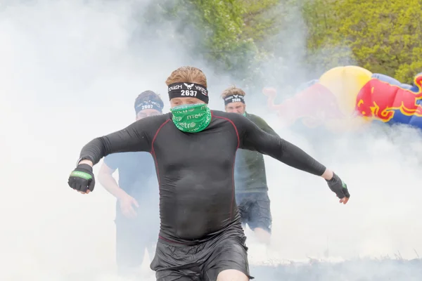 Люди в черной одежде прыгают через огонь и дым — стоковое фото